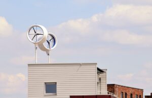 Two small wind turbines attached to the roof of a small apartment building
