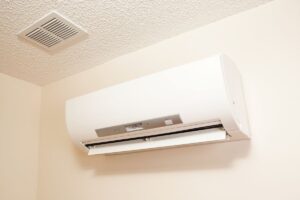 A mini-split air handler in the corner of a room just below the ceiling with a vent installed