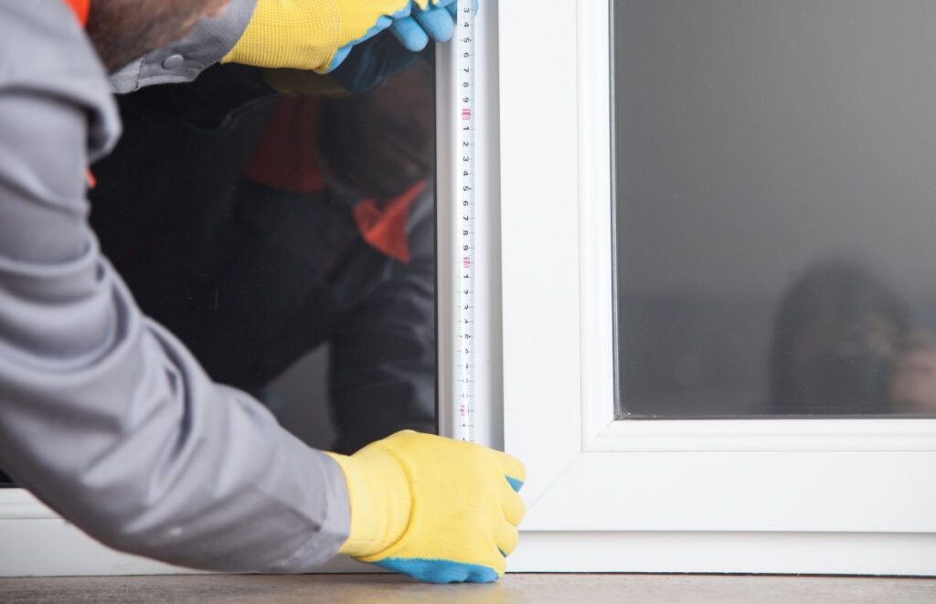 A professional measuring the height of a hurricane window during installation