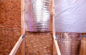 Several radiant barrier squares being installed on OSB over a wall in a home