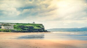 A picturesque view of the Irish coast with sandy beaches, cliffs, and lush green plateaus