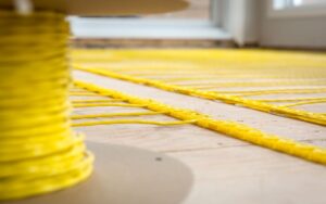 Closeup on a spool of electric radiant floor heating wire and its application in a floor