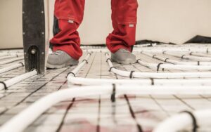 Closeup on an exposed hydronic radiant floor and the homeowner's feet who is installing it.