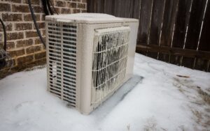 A mini-split compressor unit outside a home in wintery conditions