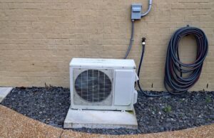 The condenser unit of a mini-split next to a wall outside a home
