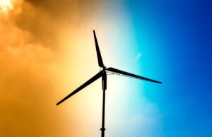 Closeup on the motor and blades of a small wind turbine with an orange-blue gradient sky behind it