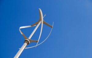A vertical axis small wind turbine against a blue sky