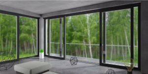 Full height patio doors with black frames in the open position, looking out onto a wooded area.