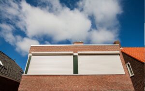 The front of a building with hurricane shutters rolled down over the windows