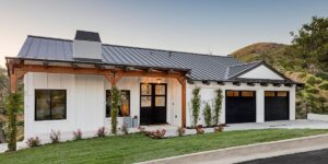 Single storey prefab modular farmhouse with gray roof, white walls and small green lawn in front.