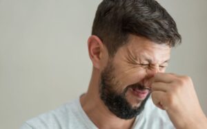 Headshot of a homeowner holding his nose, likely due to sewage smells coming from a drain