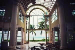 Looking out towards the back entry at the bay from the interior of a home with hurricane damage through various impact windows in place