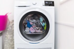 A condenser or a heat pump dryer with a glass door, which is full of clothes.