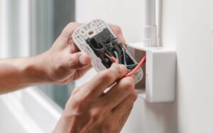 Closeup on a homeowners hands rewiring an outlet in the process of converting to an all-electric home