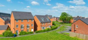 A row of homes in England with green grass in front and blue skies behind