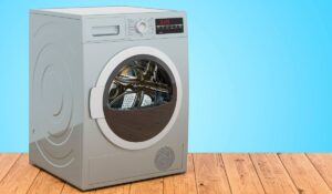 A heat pump dryer in the corner of an eggshell blue-walled room