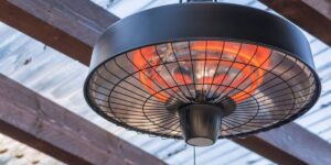 A circular radiant ceiling heater with black casing and protective cage.
