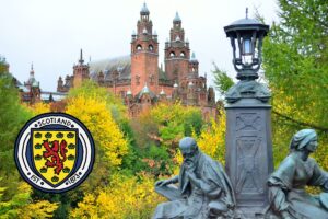 a brand symbol for Scotland in front of a scenery picture of a castle with a statue of two people on the right