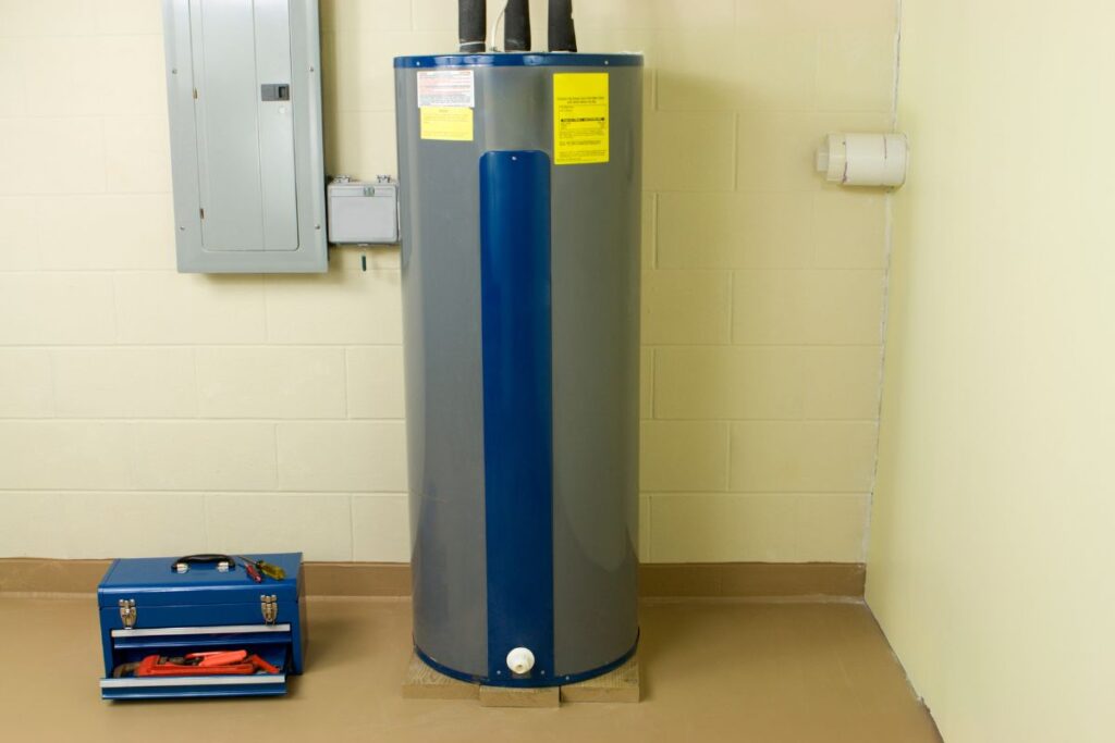 A water Heater in a basement with water heater insulation attached to the pipes on top