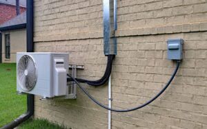 A mini-split compressor mounted on the exterior of a home