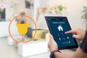 a tablet held up showing hands touching buttons, controlling the home's electrical features, along with a graphic of an electric plug on the left side