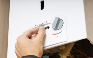 Closeup on the bottom of a water heater as a homeowner adjusts the temperature