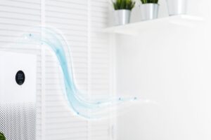 An air purifier standing on the floor with cartoon waves flowing out of it to indicate clean air being blown into the room.