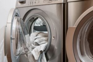 Closeup on the open door of a heat pump dryer and some towels halfway-loaded