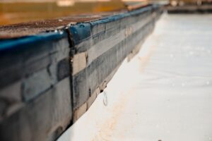 Closeup on the edge of a vapor barrier where it meets a wooden baseboard