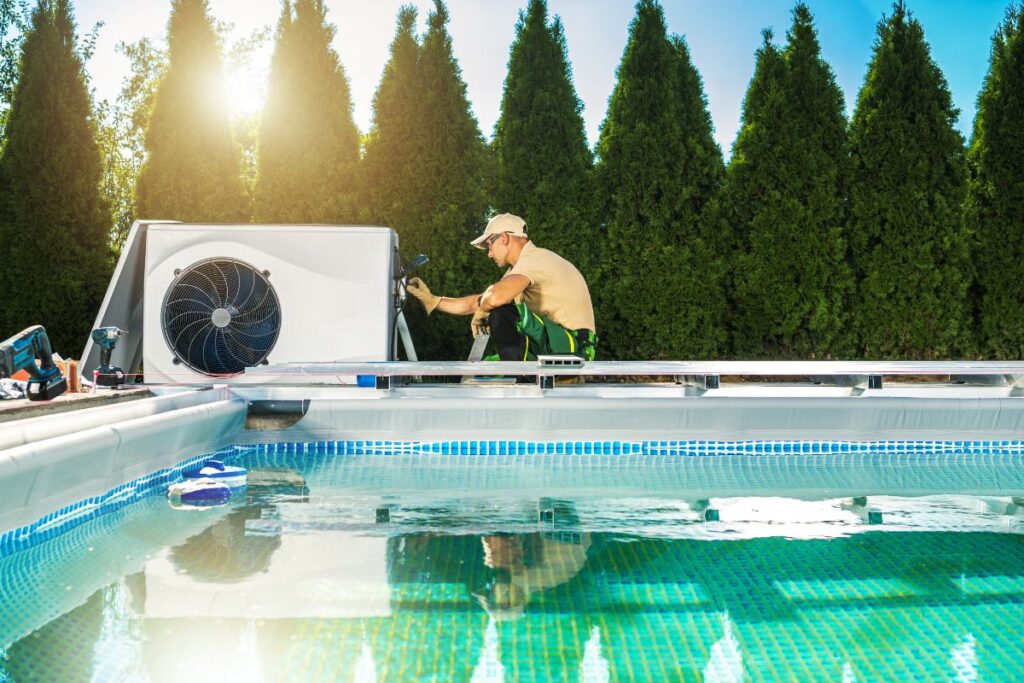 A technician installing a heat pump condenser unit outside next to a pool in a backyard