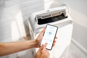 A homeowner using a smartphone to adjust her dehumidifier's settings