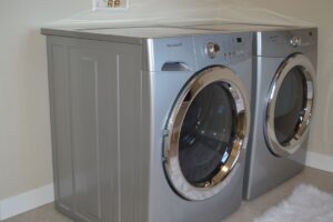condenser dryers side by side. The machines are silver and have large front-loading doors