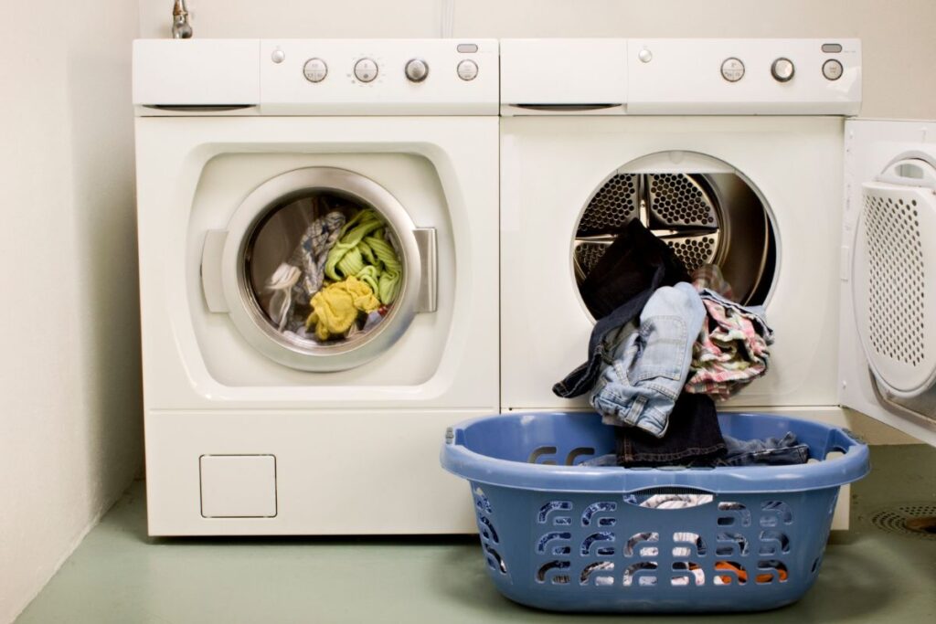 A washing machine and on open-doored, partially-loaded heat pump dryer side-by-side in a laundry room