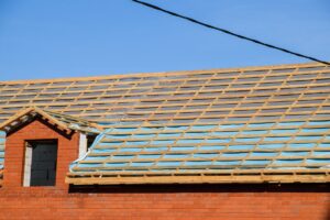 The roof of a home under construction with a vapor barrier partially installed