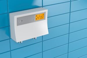 A tankless water heater's control mechanism mounted on a blue bathroom wall