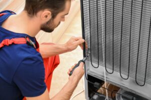 A worker services refrigerator condenser coils