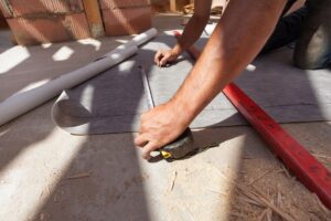 A worker measuring a roll of vapor barrier in preparation to cut it