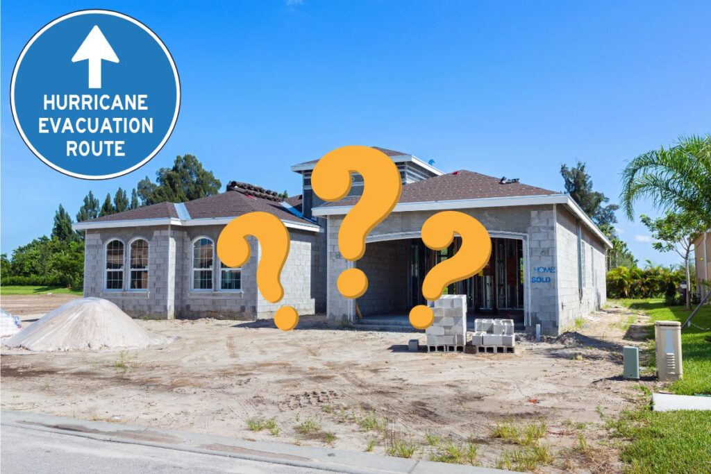 a unfinished concrete block home sitting on a sandy lot, with a sign in the middle that says hurricane evacuation zone