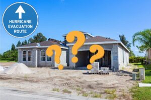 a unfinished concrete block home sitting on a sandy lot, with a sign in the middle that says hurricane evacuation zone
