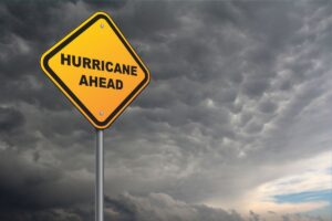 A caution sign reading "hurricane ahead" transposed in front of some ominous-looking clouds