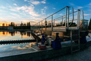 A modern wastewater treatment facility with a setting sun in the background