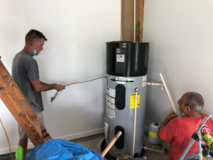 two men installing a heat pump water heater in a garage