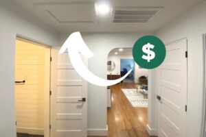 a picture of a hallway in a house with a white graphic arrow and a dollar sign pointing to the attic hatch