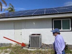 a man in a purple shirt walking the property of our netzero home, and checking out the hurricane pad for the hvac unit after hurricane ian