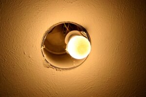 Closeup on a glowing A19 light bulb in a recessed can fixture in the ceiling