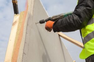 A worker drilling into a SIP being used in a home under construction