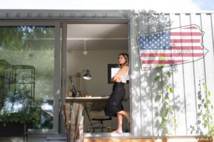 The homeowner of a container home leaning on an opening in the entryway