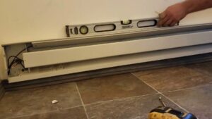 Closeup on a baseboard heating unit being installed with a level on top
