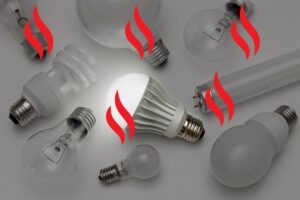 An array of light bulb varieties with the LED bulb at center illuminated, and red heat symbols transposed over the image